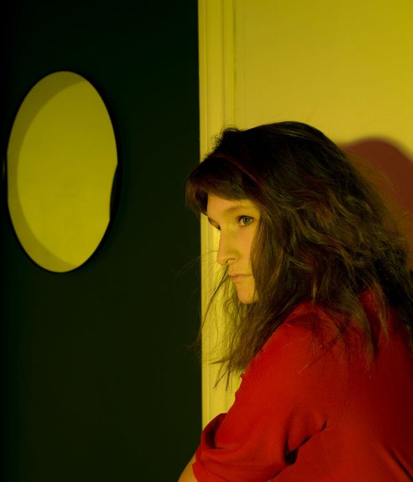 Woman in a calm yoga pose in a dark room with honey-colored light.